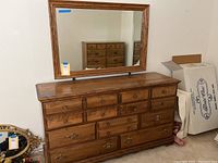 Front view of wooden dresser with attached mirror showing drawer layout and wood grain finish.