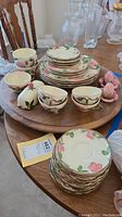 Full view of dinnerware including stacked plates, cups, and saucers displayed on Lazy Susan.