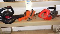 Photo of two electric hedge trimmers and a Toro Power Sweep blower on a shelf