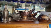 Side view showing silver plated gravy boats with handles on matching tray, silver cocktail shaker, salt and pepper shakers