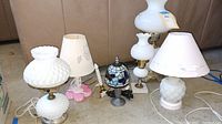 Group photo showing six assorted lamps on the floor with couch background.