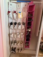 View of approximately 18 pairs of women's shoes stored in white and pink hanging shoe organizers