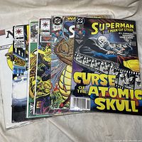 Photo showing a stack of 8 comic books including Superman, Valiant, Marvel, and DC Comics titles.