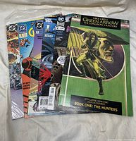 Photo of assortment of 8 comic books showing covers including Green Arrow Longbow Hunters and several DC Universe titles.