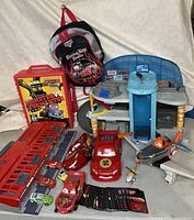 Full display of Disney Pixar Cars lot including multiple vehicles, playsets, accessories, and backpack.