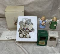 Lot items arranged showing Lenox Snowy Day elephant figurine in styrofoam, two Goebel angel bell figurines, original boxes and certificate for Lenox.