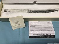 Original Lenox box containing the cake slicer with use and care instruction pamphlets and warranty information.