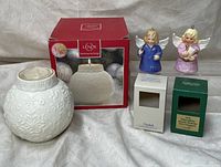 Photo showing Lenox Ornamental Glow white snowflake candle holder with its original box and two Goebel angel bell ceramic figurines, one in blue robe and one in pink robe.