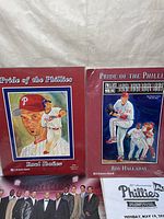 Photo showing two posters titled 'Pride of the Phillies' featuring Raul Ibanez and Roy Halladay with painted portraits on red background