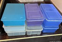 Stack of 10 plastic storage boxes in various colors including blue, purple and clear translucent plastic.