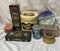 Photo showing nine assorted vintage collectible tins including White Horse Whiskey rectangular tin, Charles Chips large round tin, and other decorative tins.