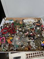 Box of mixed vintage to modern broken jewelry and craft beads, showing various colorful pieces, metal parts, and strands piled together.