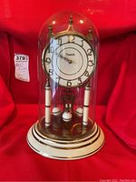 Front view of vintage anniversary clock with glass dome showing clock face and dial