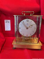 Front and angled view of vintage anniversary clock with brass finish and glass dome, showing the clock face, hands, and overall condition.