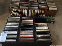 Photo showing rows of various CDs stacked in trays and boxes, visibly different album covers and labels.