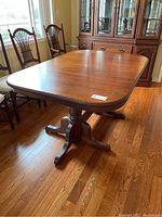 Assembled rectangular table top on hardwood floor under window, two pedestal supports visible