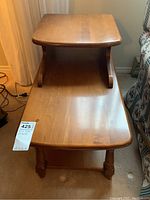 Front view of wooden two-tier end table showing top and lower shelf, with visible wood grain and rounded corners.