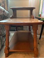 Front view of wooden end table showing lower shelf and upper curved shelf structure.