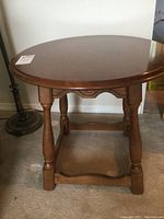 Front view of round wooden end table showing circular top and four turned legs
