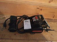 Photo of a black electric jig saw with label and cord, placed on a wooden surface.