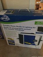 Box showing Optex Portable Photo Studio & Lighting Kit, compact all-in-one light studio for photography with integrated carrying case.