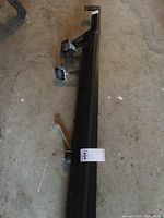 Side view of black metal queen size bed frame showing attached wheels and part of the frame structure