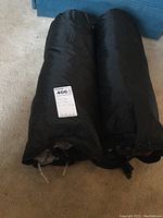 Two black rolled tents in carrying bags