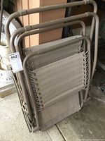 Folded zero gravity chair showing metal frame and woven fabric seating, some wear and dust visible.