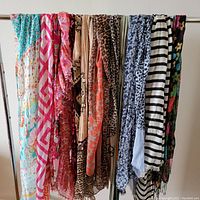 Photo of 12 scarves hanging on a bar showing various patterns and colors including floral, geometric, stripes, and animal prints.