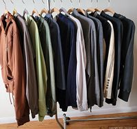 Front view of 12 women's hoodies and matching pants sets hanging on clothing rack, showing variety of colors and styles.