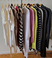 Front view of 14 women's long sleeve knits and sweaters hanging on a rack, showing variety of colors, styles, and materials