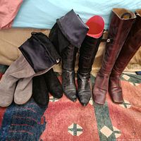 Top-down image of 4 pairs of women's tall boots showing different colors and styles including gray suede, black smooth, black leather pointed toe with red lining, and brown leather boots.