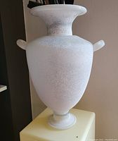 Close-up of the urn-shaped glass vase showing its texture, shape and handles.