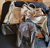 Photo showing group of 5 handbags in various materials, sizes, and colors laid out on a black surface.