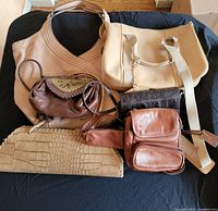 Photo showing all six handbags and purses arranged to display variety of sizes and styles on black surface.