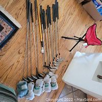 All clubs and headcovers laid out on wood floor with tripod stool