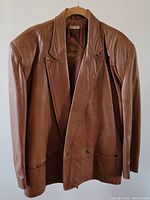 Front view of Le Compagnons caramel leather jacket, showing double-breasted button closure and two front pockets.