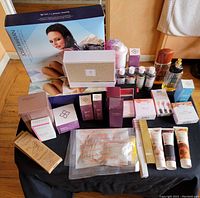 Photo showing variety of toiletries and skincare products arranged on black surface including boxed Josie Maran product, Laura Geller and Serious Skincare products, two opened perfume bottles, tubes of creams and small bottles.