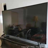 Front view of the TCL Roku TV showing the full screen and stand placed on a dresser.