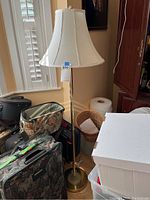 Full view of the floor lamp placed beside suitcases and baskets indoors to show overall size and design.