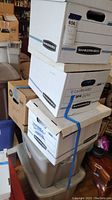 Four boxes stacked on top of two plastic bins, containing clothing as indicated on labels and seller description.