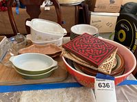 Photo showing the Pyrex red large mixing bowl, Corning Ware oval dishes with floral design, several smaller bowls stacked inside, and ceramic coasters on top.