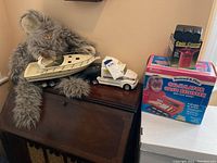 Wide shot showing stuffed bunny holding Tiara toy boat and truck, Coin Count Junior and cash register boxes nearby.
