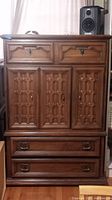 Front view of vintage solid wood chifferobe dresser showing carved panels and metal drawer pulls.