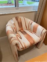 Front view of the armchair showing the orange swirl pattern upholstery and rounded shape.