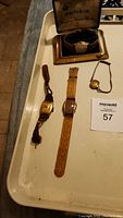 Overview of all four watches: one women's dainty watch, three men's vintage/antique watches including one in a brass display box