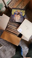 Box filled with vintage vinyl records stacked vertically, including a Santana album on top showing wear.