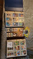 Open binder showing baseball cards in plastic sleeves, mostly grouped by player and team, organized for viewing