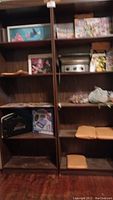 Two tall wooden book shelves with backs containing comic books, board games, framed Finding Nemo artwork, and other items.