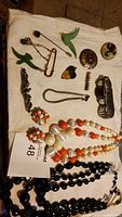 Photo showing assorted vintage costume jewelry items arranged on fabric, including necklaces and brooches.